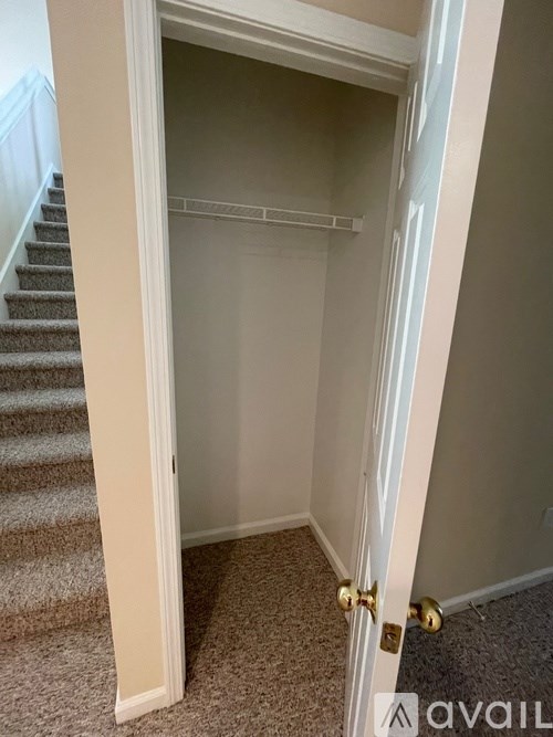 A white door with a gold handle is open to a hallway.