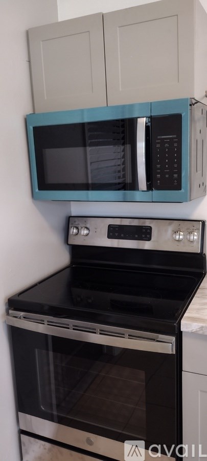 A kitchen with a black stove top oven and a black microwave above it.