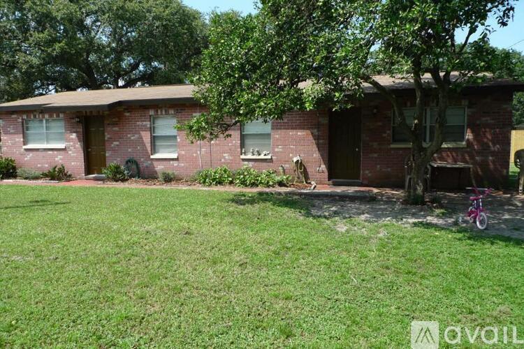A house with a red brick exterior and a tree in front.