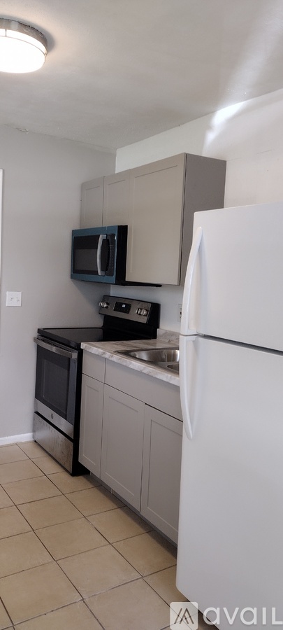 A kitchen with a white refrigerator, black microwave, and a black oven.
