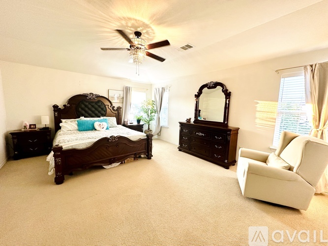 A bedroom with a large bed, a dresser, and a chair.
