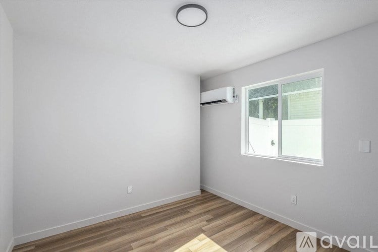 A room with a window and a wooden floor.