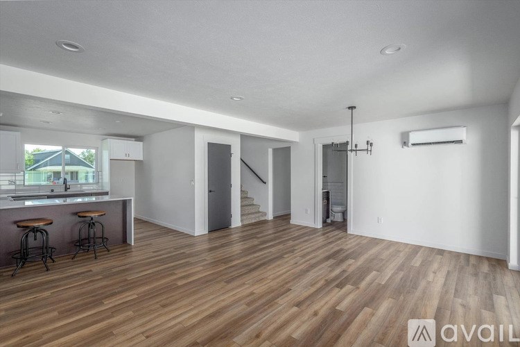 A spacious room with wooden flooring and white walls.
