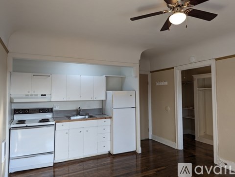 A kitchen with white appliances and cabinets with a ceiling fan.