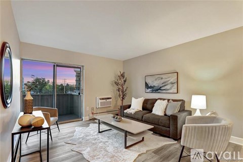 A living room with a brown couch, a white chair, a coffee table, and a painting on the wall.
