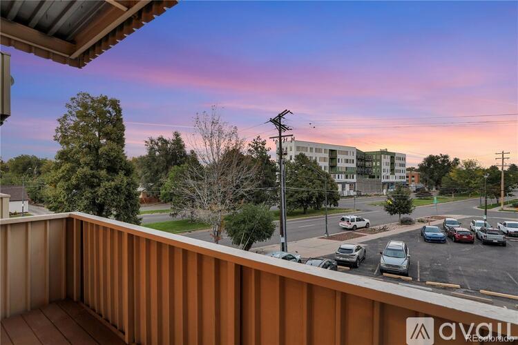 A view from a balcony overlooking a parking lot and a building with the sign "avail" on it.