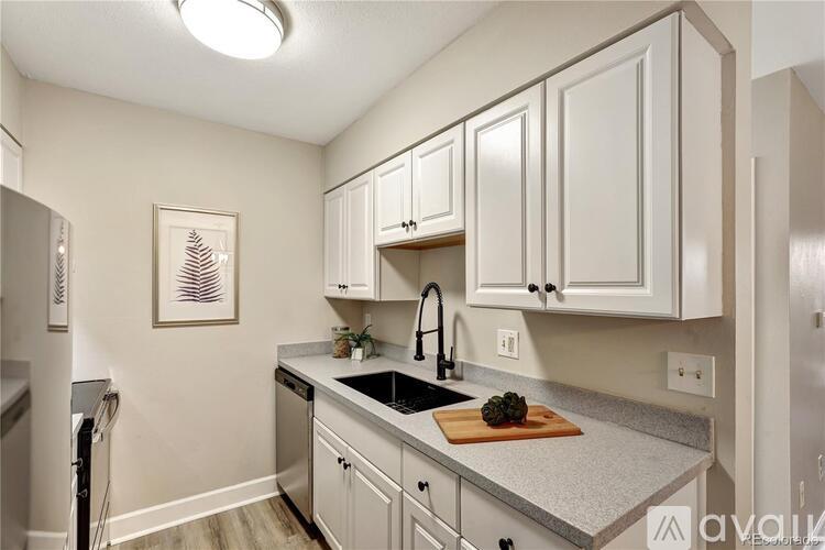 A kitchen with white cabinets and a wooden cutting board on the counter.