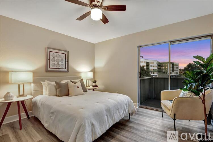A bedroom with a large bed, a ceiling fan, and a view of the city through the window.