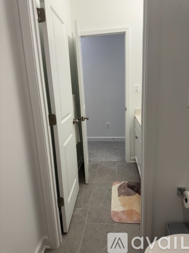 A hallway with a door on the left and a toilet on the right.