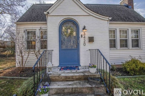 A white house with a blue door and a black metal railing.