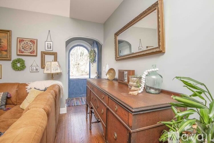 A living room with a brown couch, a wooden desk, and a mirror on the wall.