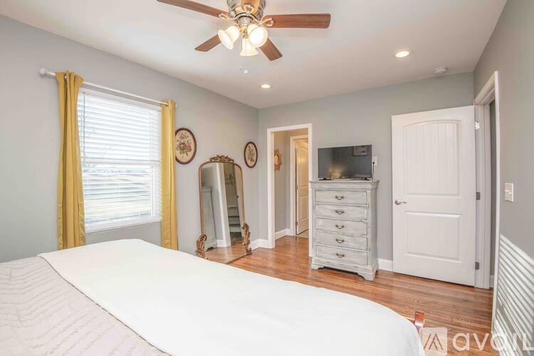A bedroom with a large bed, a dresser, and a ceiling fan.