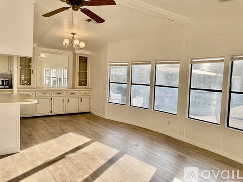 A spacious kitchen with a ceiling fan and large windows.