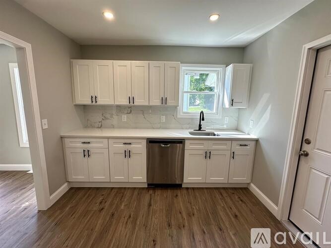 A kitchen with white cabinets and a wooden floor.