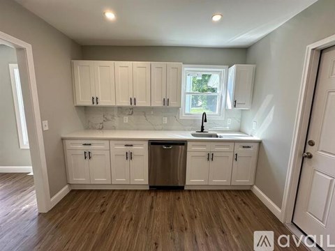 A kitchen with white cabinets and a wooden floor.