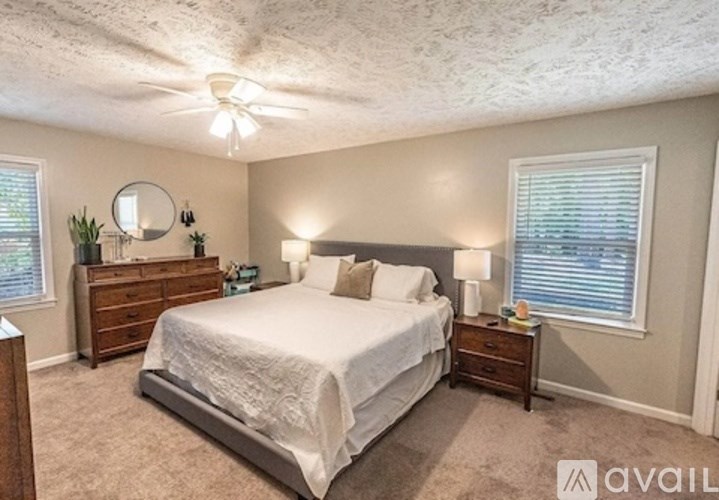 A bedroom with a large bed, a dresser, and a ceiling fan.