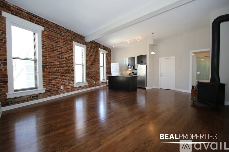 A spacious room with wooden floors and brick walls.