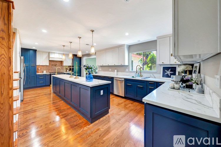 A kitchen with dark blue cabinets and wooden floors.