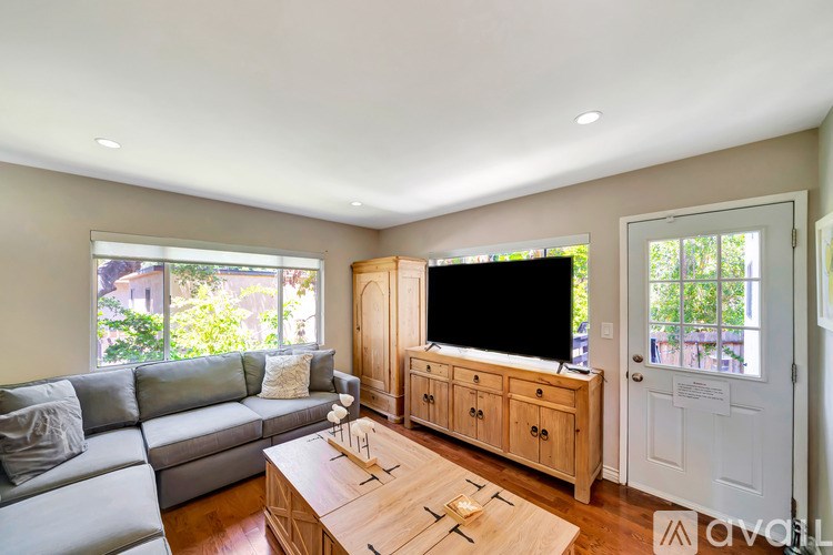 A living room with a grey couch, wooden coffee table, and a flat screen TV.