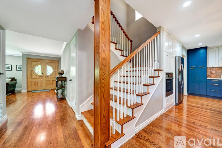 A wooden staircase with white railings leads to a second floor.
