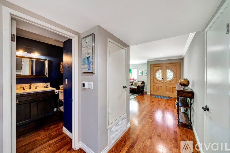 A hallway with a wooden floor and white walls leading to a door.