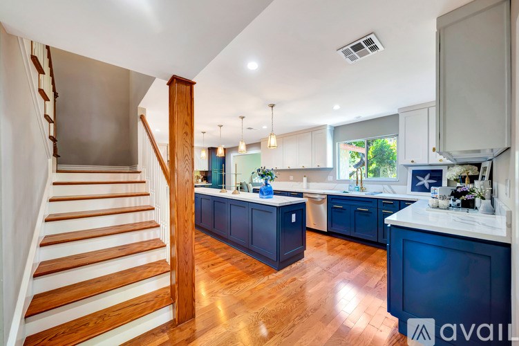 A kitchen with dark blue cabinets and a wooden staircase.