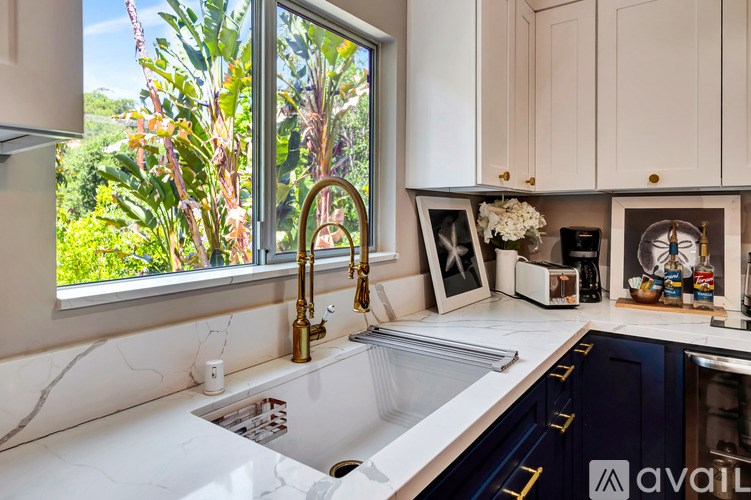 A kitchen with a sink and a window overlooking greenery.