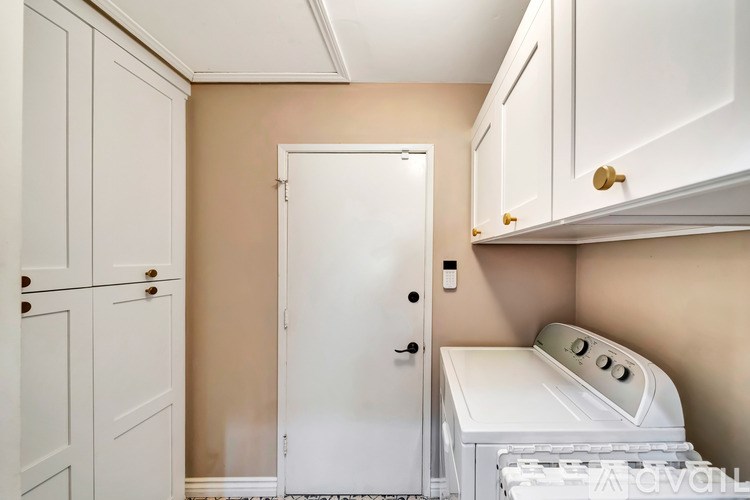 A white door is in a room with a washing machine.