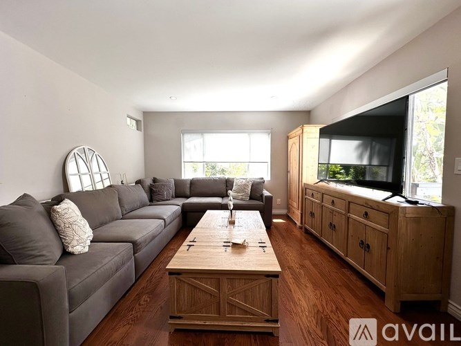 A living room with a grey couch, wooden coffee table, and a television.