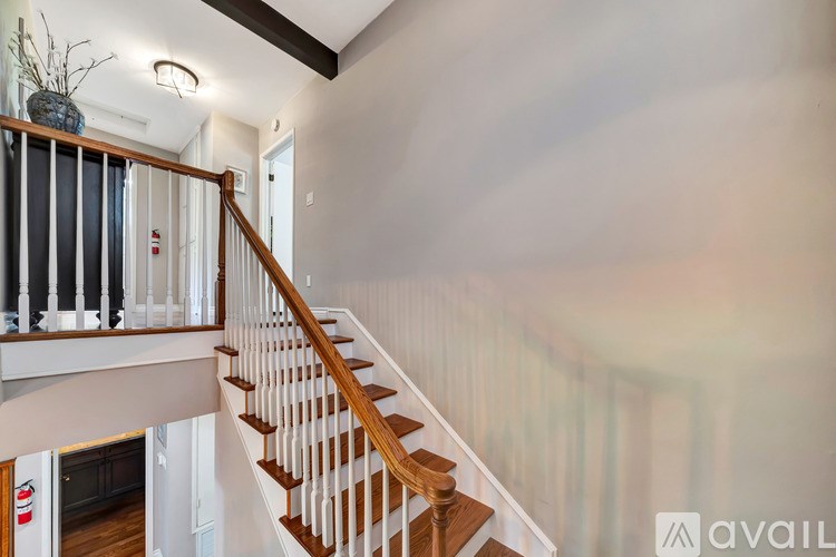 A staircase with a wooden handrail and a vase on top.