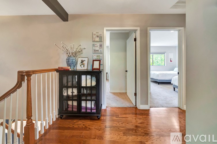 A hallway with a wooden floor and a staircase on the left.