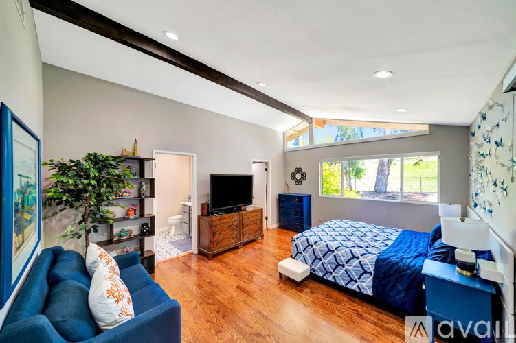 A bedroom with a blue couch and a bed with a blue comforter.