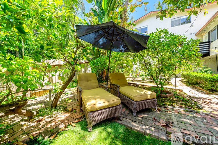 Two chairs are sitting on a patio under a black umbrella.