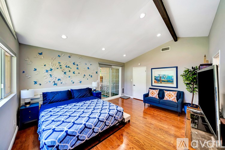 A bedroom with a blue bedspread and a blue couch.