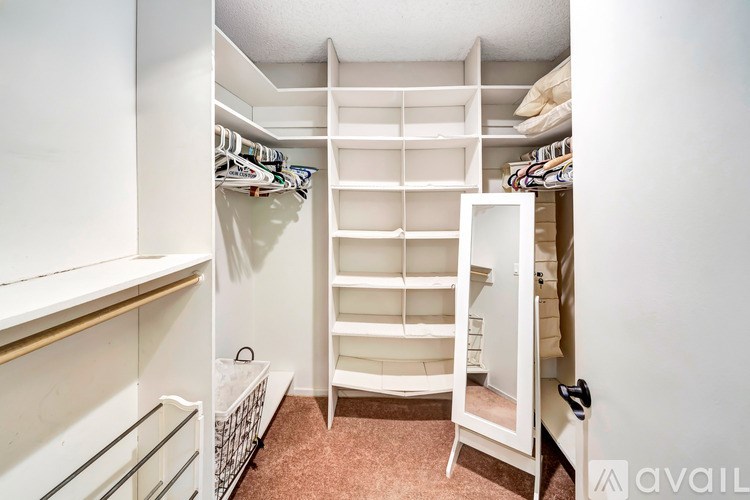 A white closet with a shelf and a white door.