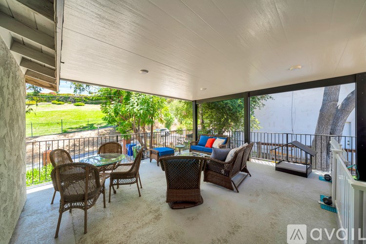 A patio with a table and chairs overlooking a grassy area.