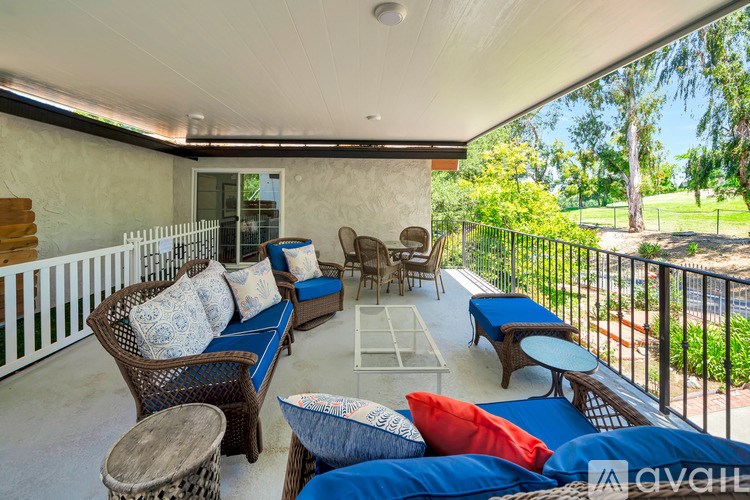 A patio with a white railing and furniture including a sofa and chairs.