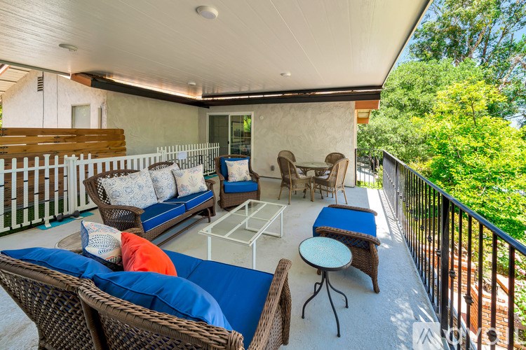 A balcony with a sofa, chairs, and a table.