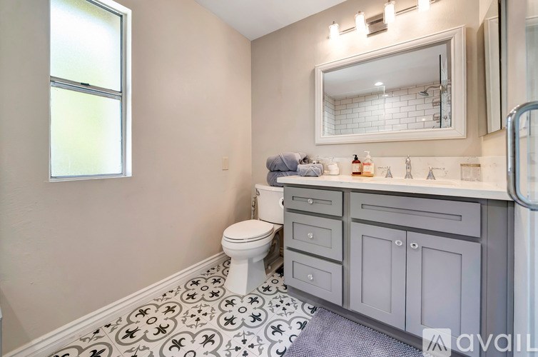 A bathroom with a toilet, sink, and a window.