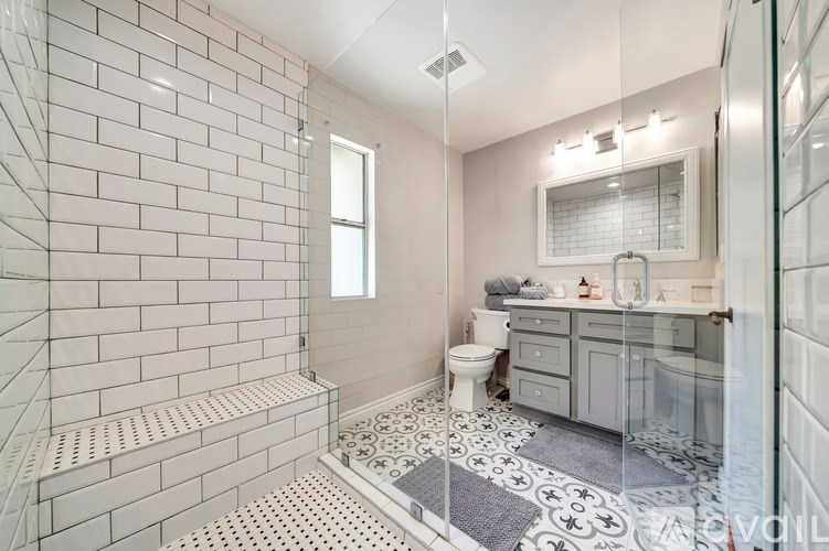 A white tiled bathroom with a walk-in shower and a toilet.