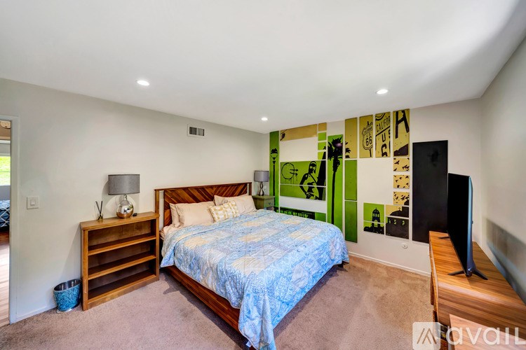 A bedroom with a bed, nightstand, and a wall with pictures.