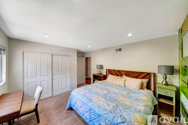 A bedroom with a bed, nightstand, and chair.