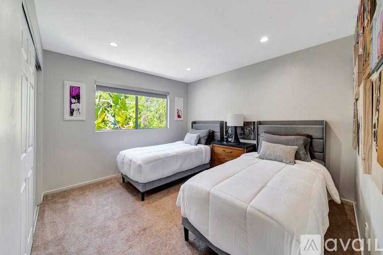 A bedroom with two beds and a window.