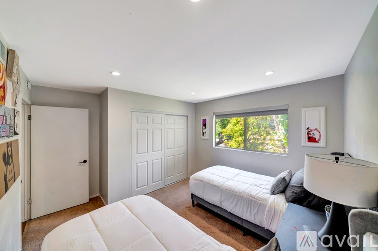 A bedroom with a bed, desk, and two doors.