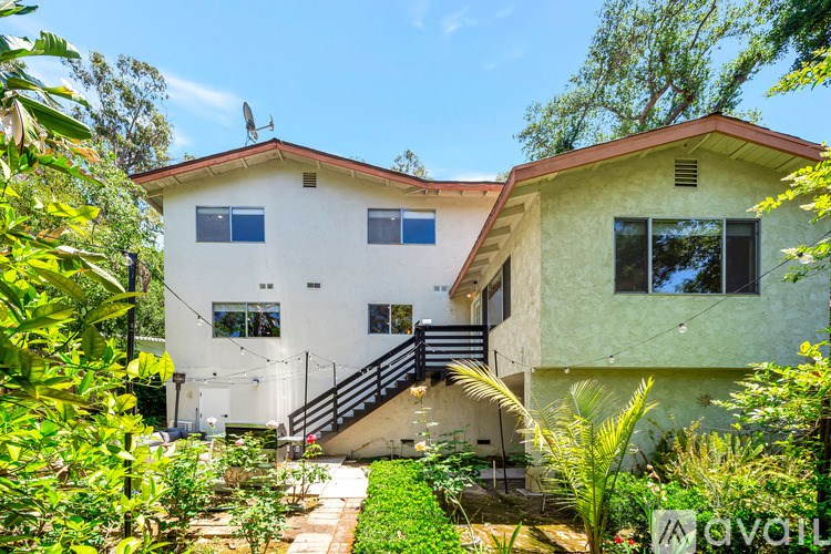 A white house with a red roof and a staircase leading to the entrance.