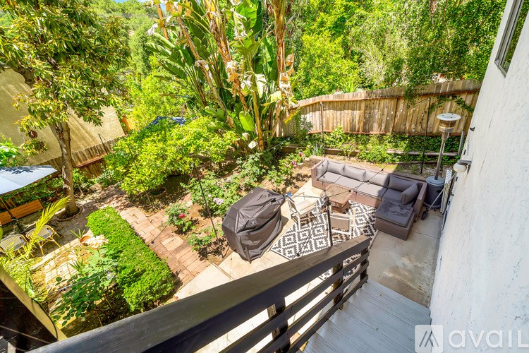 A patio with a table and chairs is surrounded by greenery.