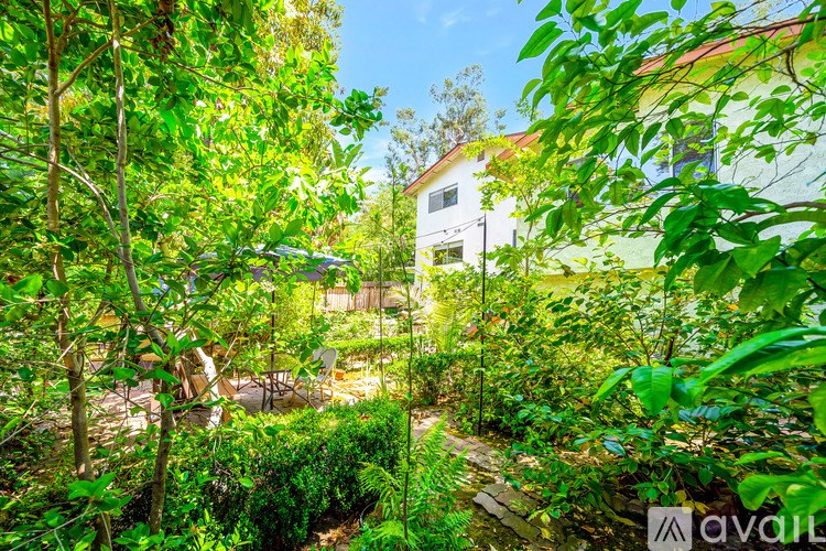 A lush green garden with a white building in the background.