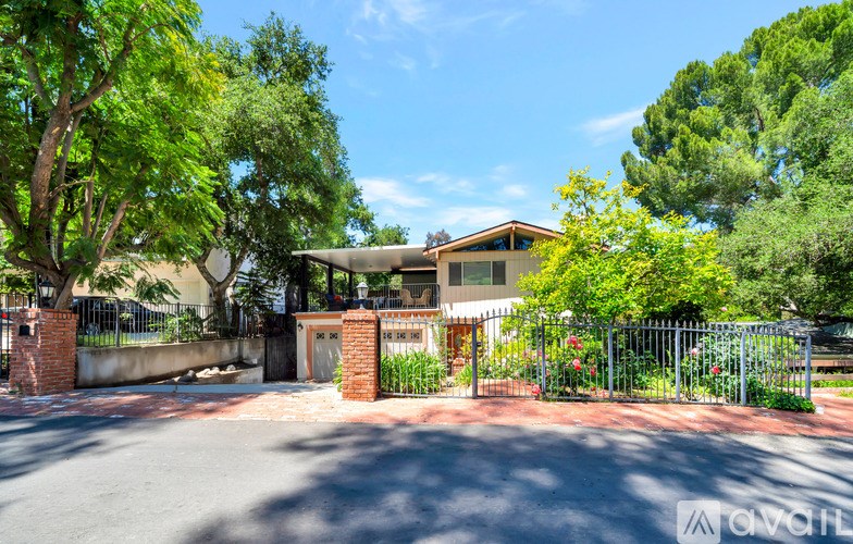 A house with a driveway and a gate surrounded by greenery.