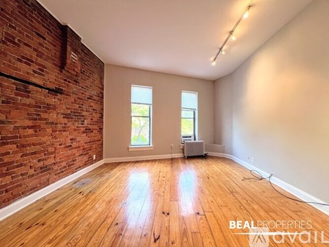 A black wood stove is in a room with a brick wall.