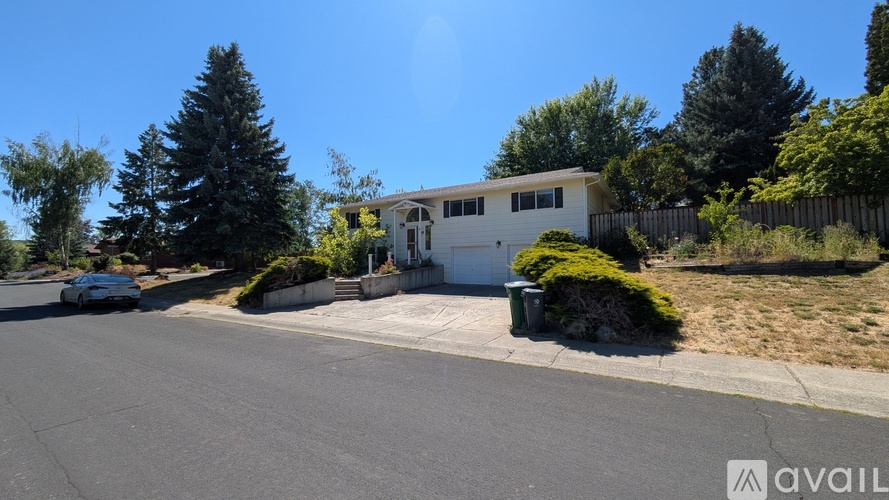 A house with a white exterior is situated on a street with a car parked in front.
